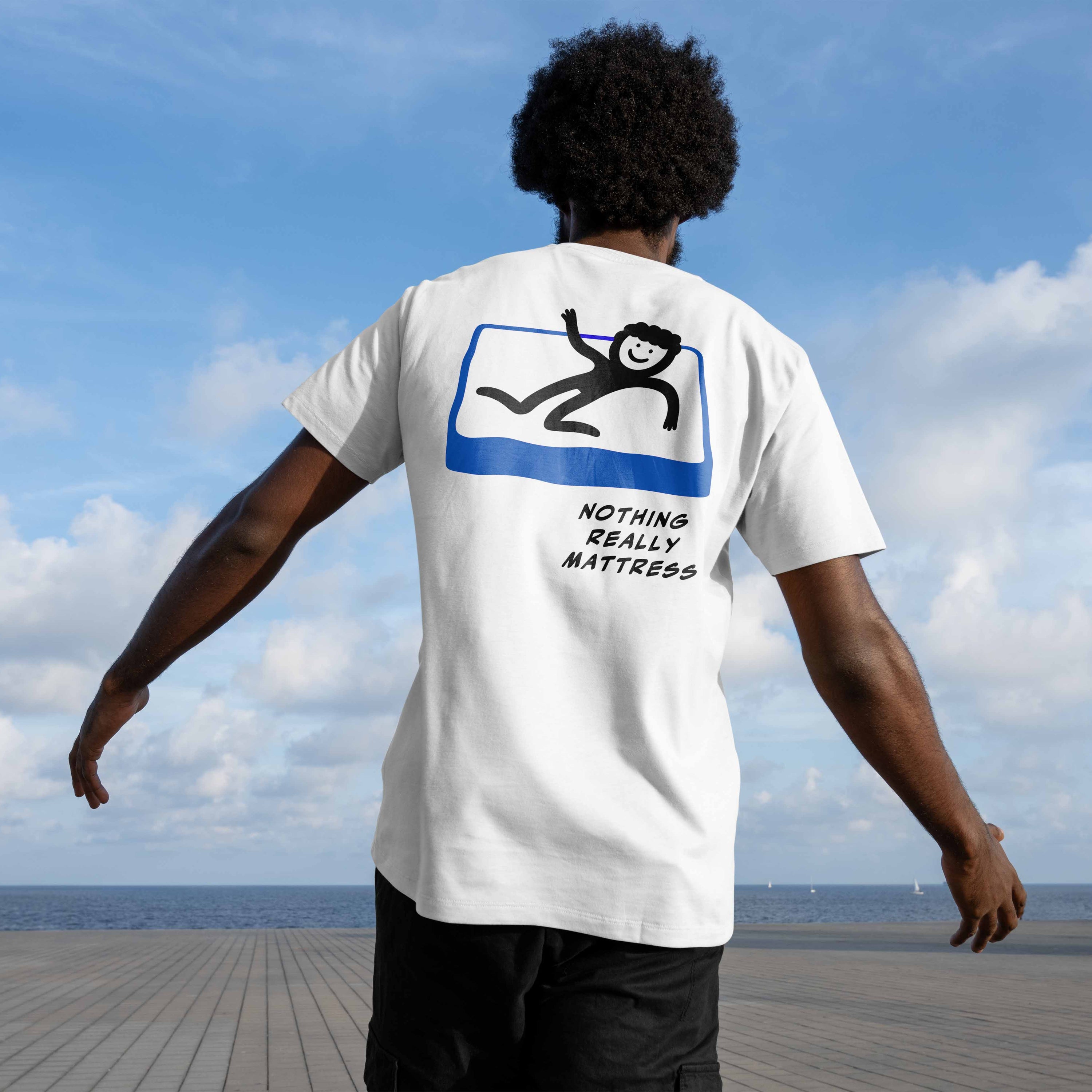 Man wearing graphic white tee featuring a smiley figure on the mattress and text "nothing really mattress". 