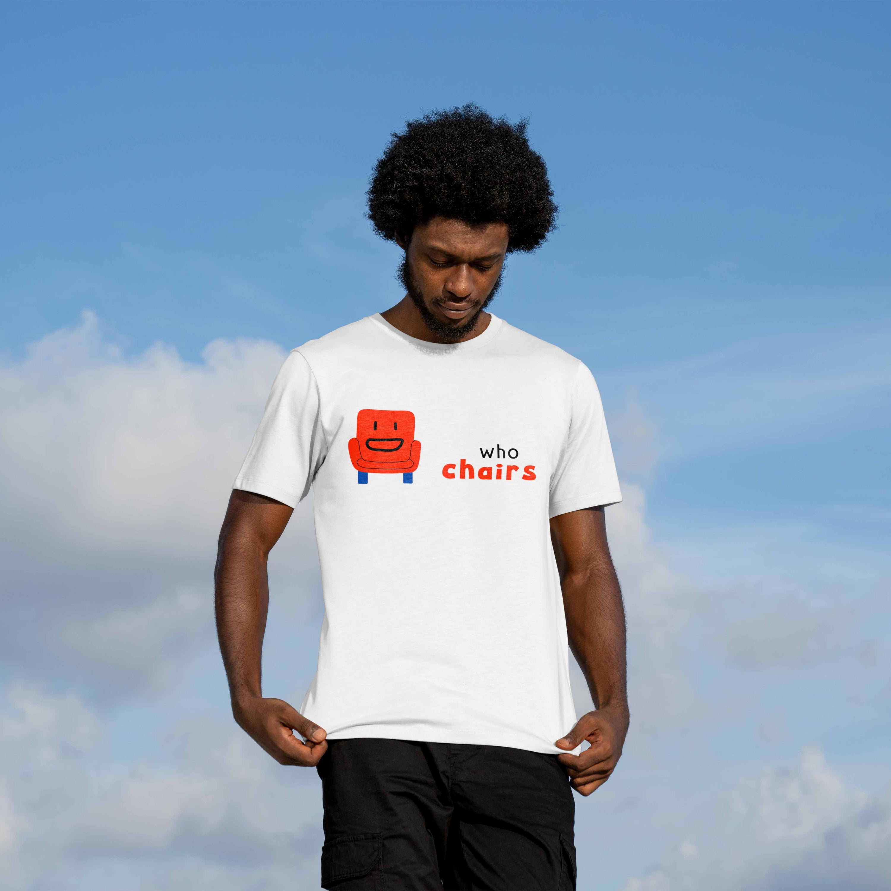 Man wearing graphic white tee featuring a cute smiling red armchair illustration with "who chairs" text in black and red